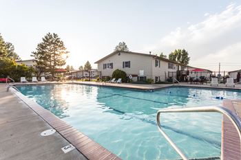 Outdoor pool at Castlerock Apartment Homes with the sun peaking through the trees in the background.